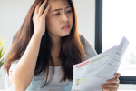 Woman with concerned look holding a stack of bills