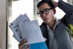 Man looking at stack of bills